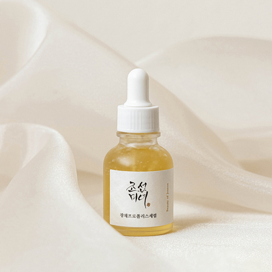 Beauty of Joseon Glow Serum Propolis & Niacinamide bottle standing tall at K-Beau against soft ivory fabric background.